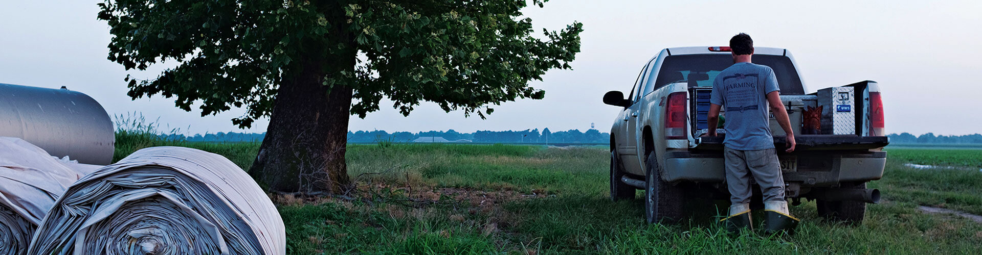 Farmer getting items from a truck while working a field.